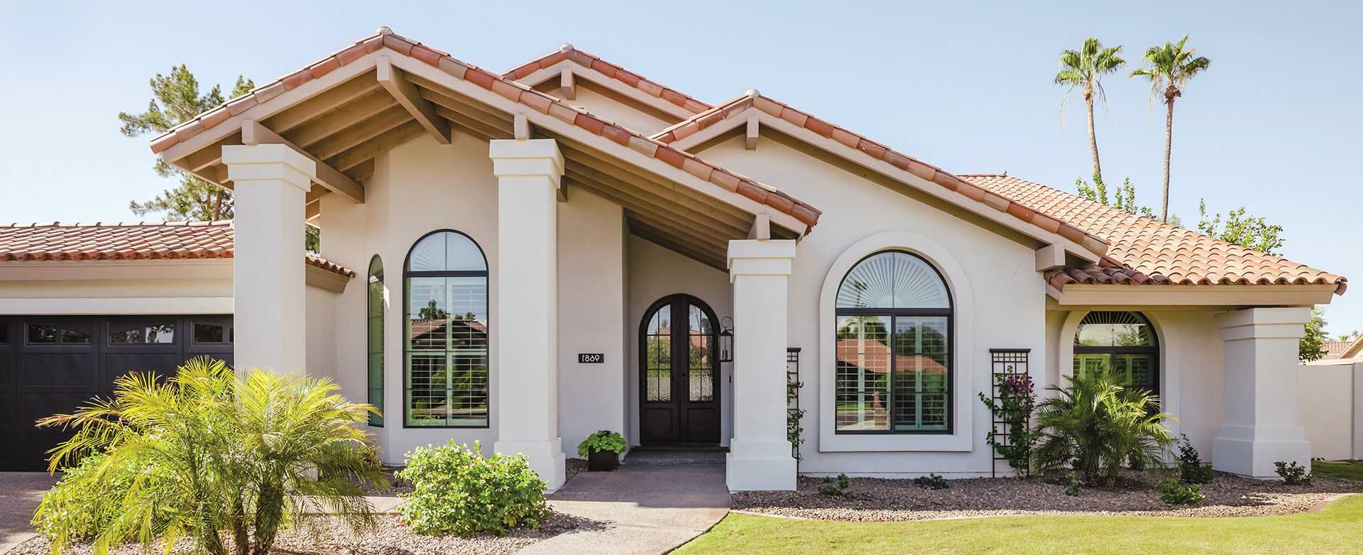 Exterior view of a white Spanish style home with arch windows.