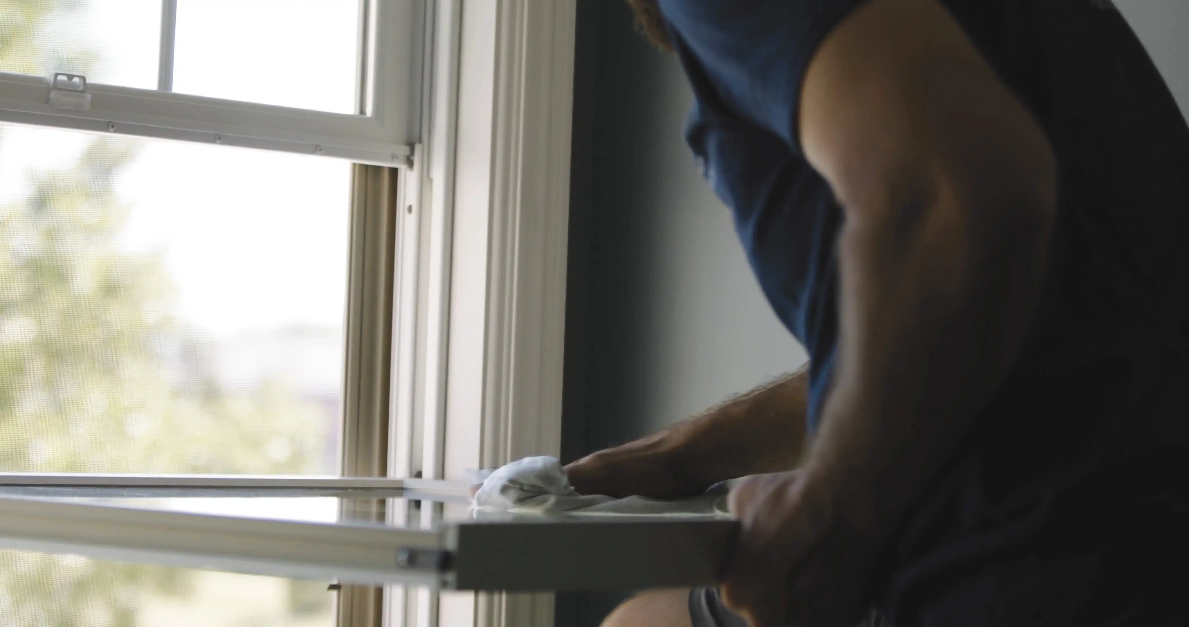 A man in a blue shirt holds on to the lower sash of a Marvin Replacement window.