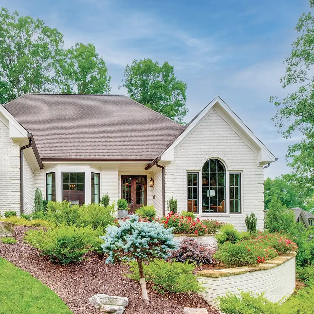 Exterior view of a white brick house with a Marvin Replacement Round Top and Special Shape window.