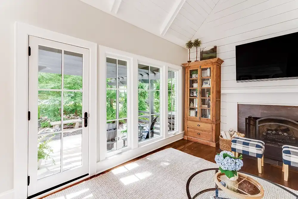 A white Marvin Replacement Inswing French door with a bronze sill and Cambridge Collection door handle