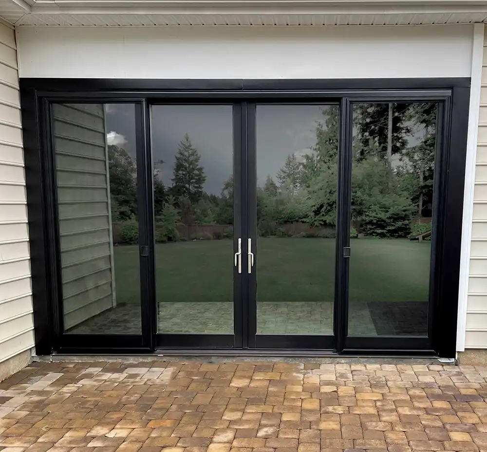 Exterior view of a black Marvin Replacement four-panel sliding French patio door installed.
