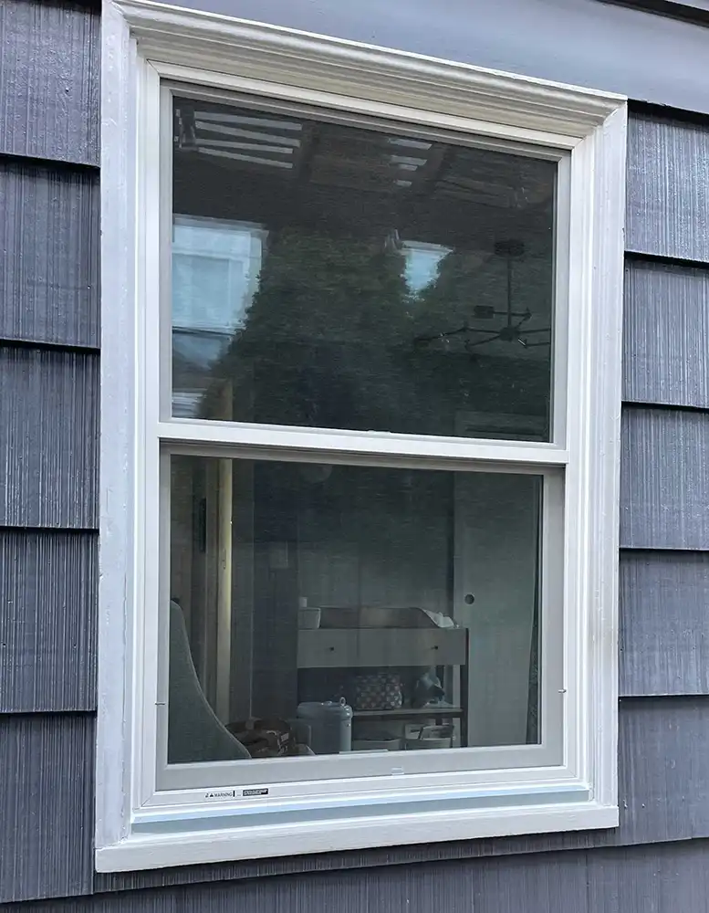 Exterior view of a Marvin Replacement Double Hung windows installed on a blue home with white trim