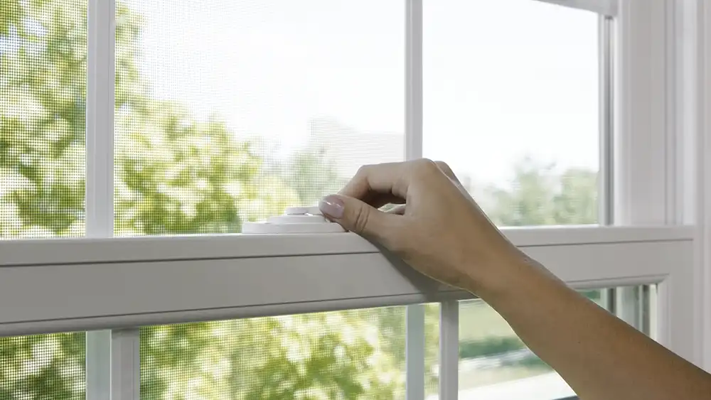 Woman closes a window latch.