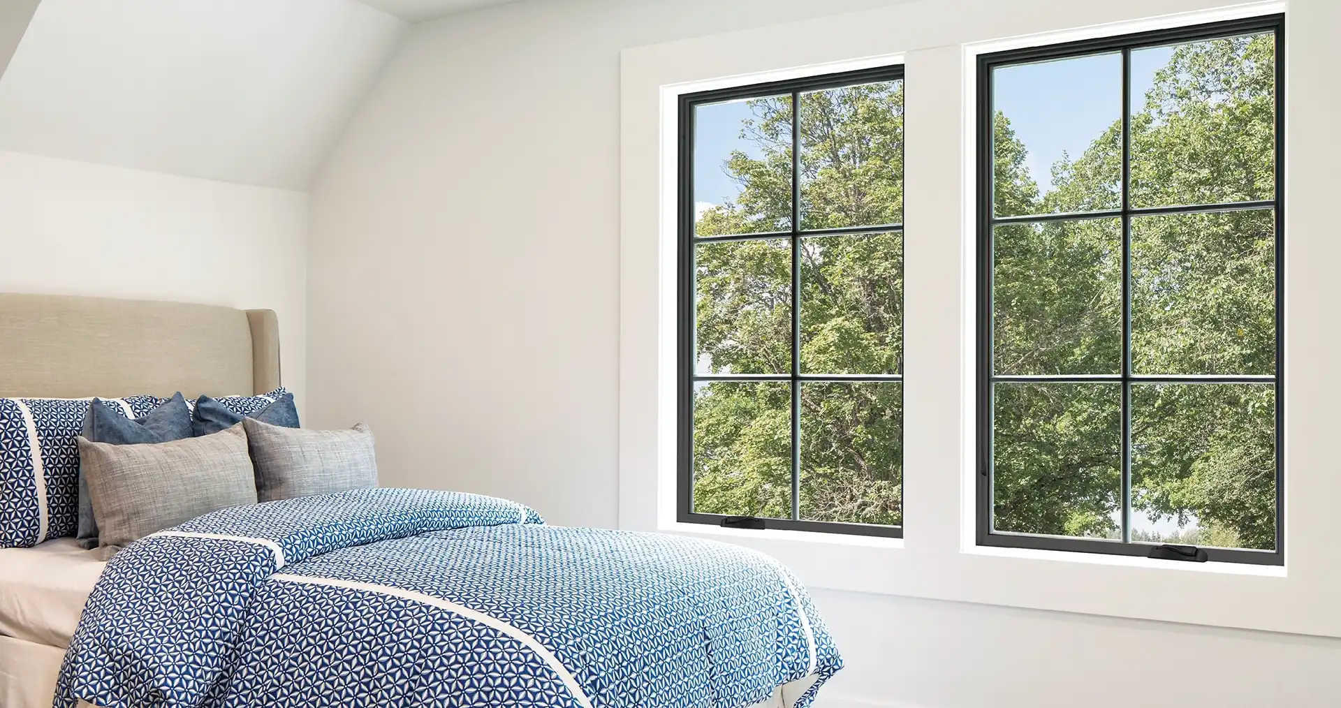 Interior view of a bedroom with two black Marvin Replacement Casement windows.