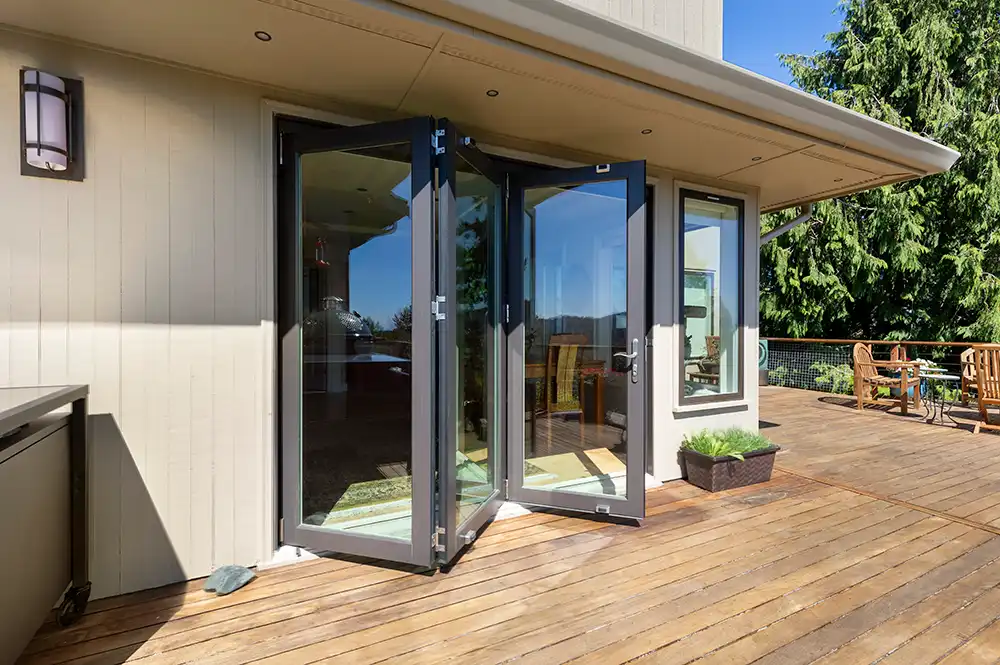 View of an opened three-panel bronze Marvin Replacement bi-fold door on a deck.