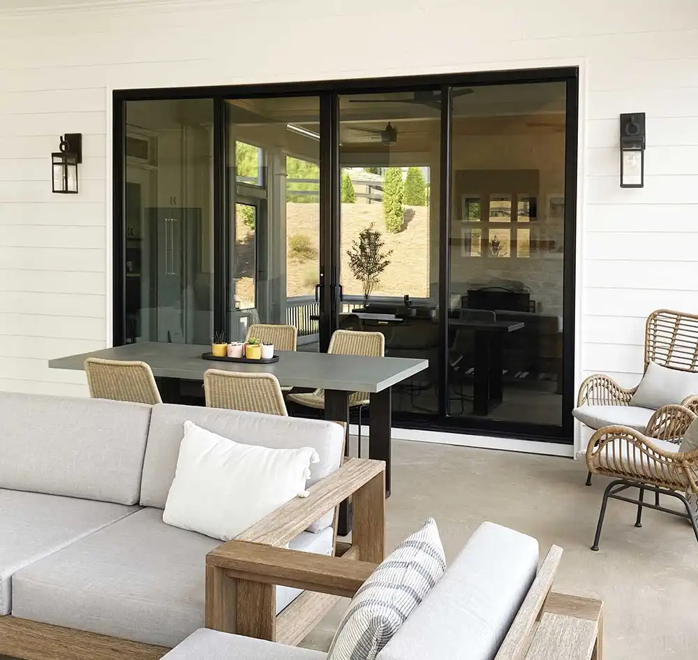 Exterior concrete porch image featuring a four-panel black Marvin Replacement Sliding Patio Door.