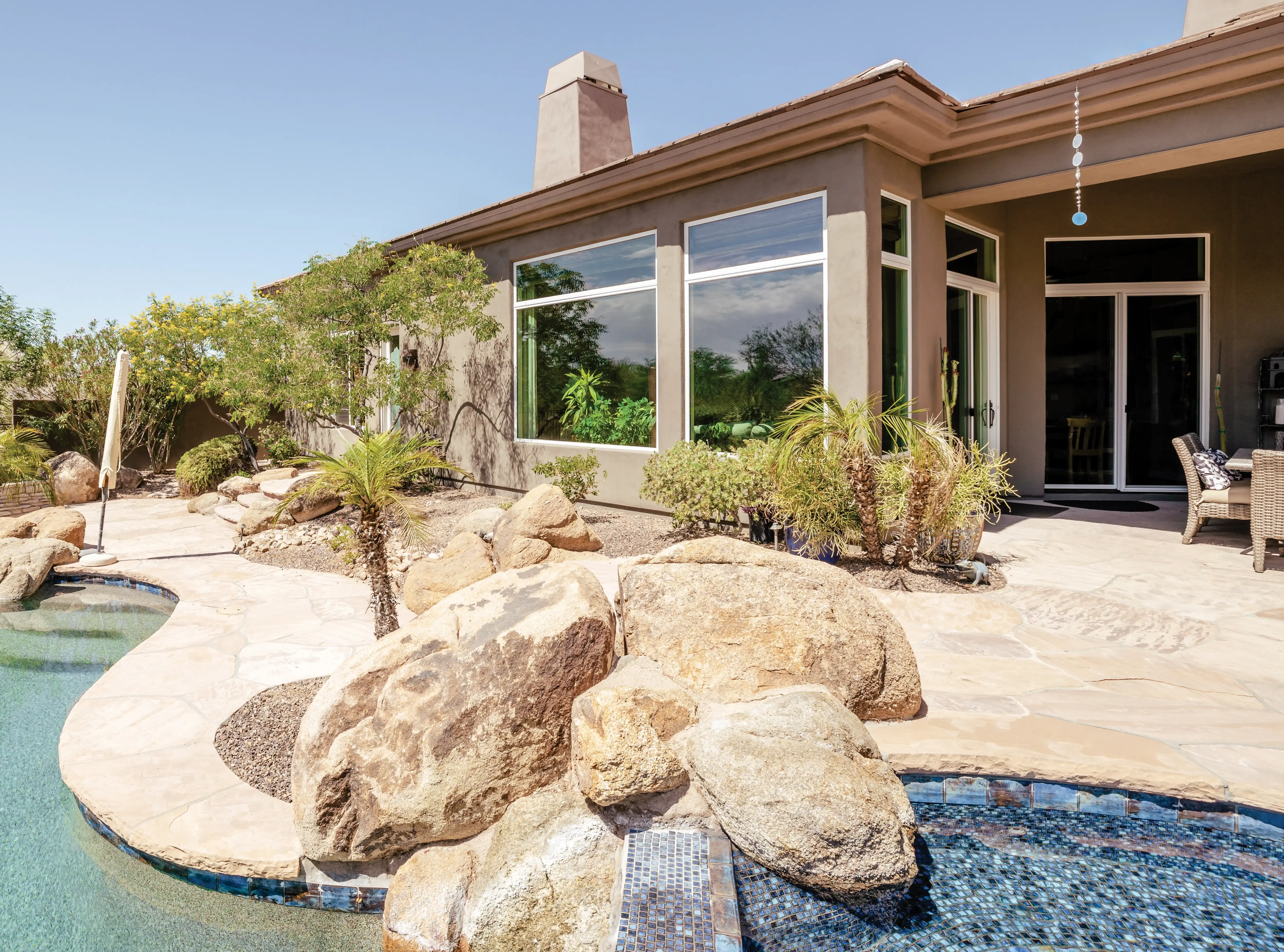Image of a home with big picture windows with a pool in the foreground.