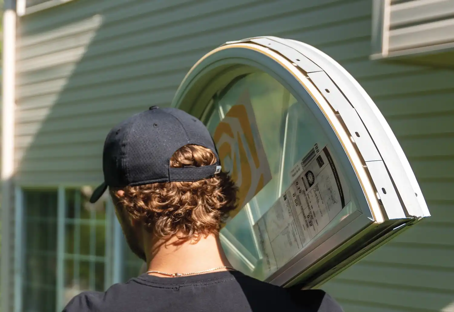 Marvin Replacement installer carrying half round window with a Marvin Replacement window label sticker.