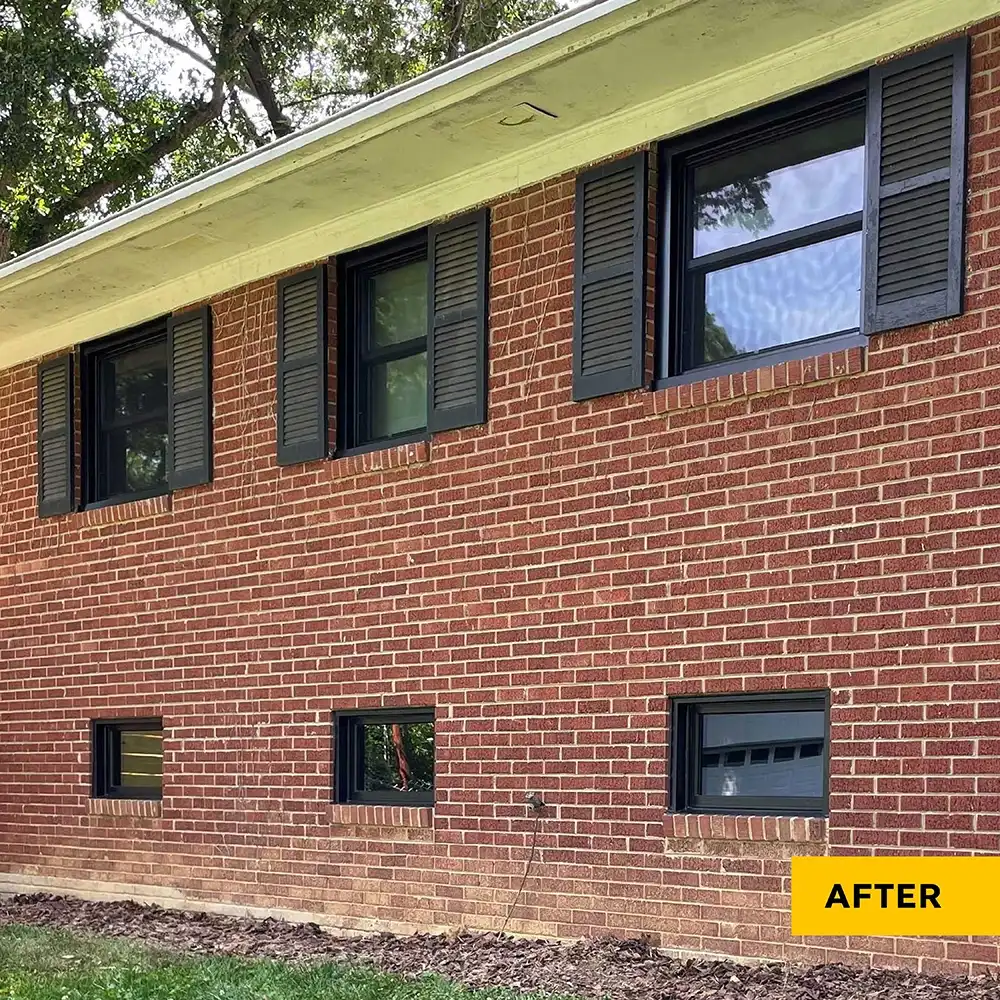 Exterior view of a brick home with black windows and black shutters.