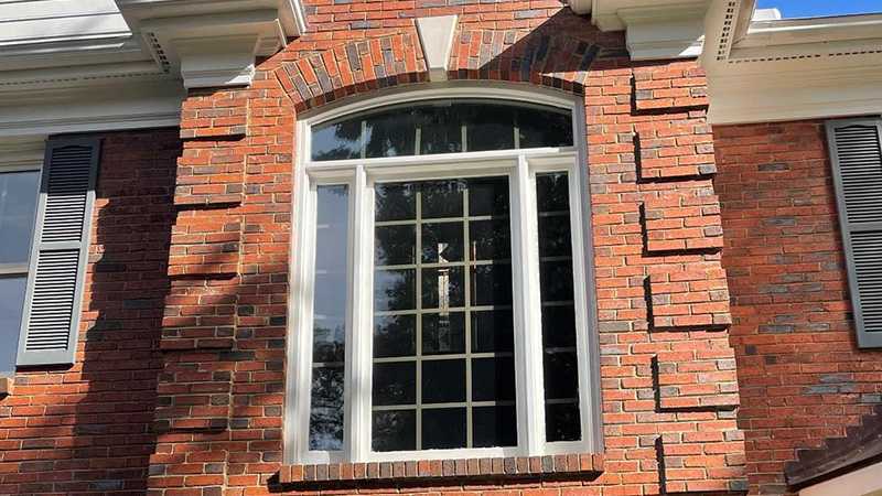 Exterior view of a picture window featuring a round top window above on a brick home.