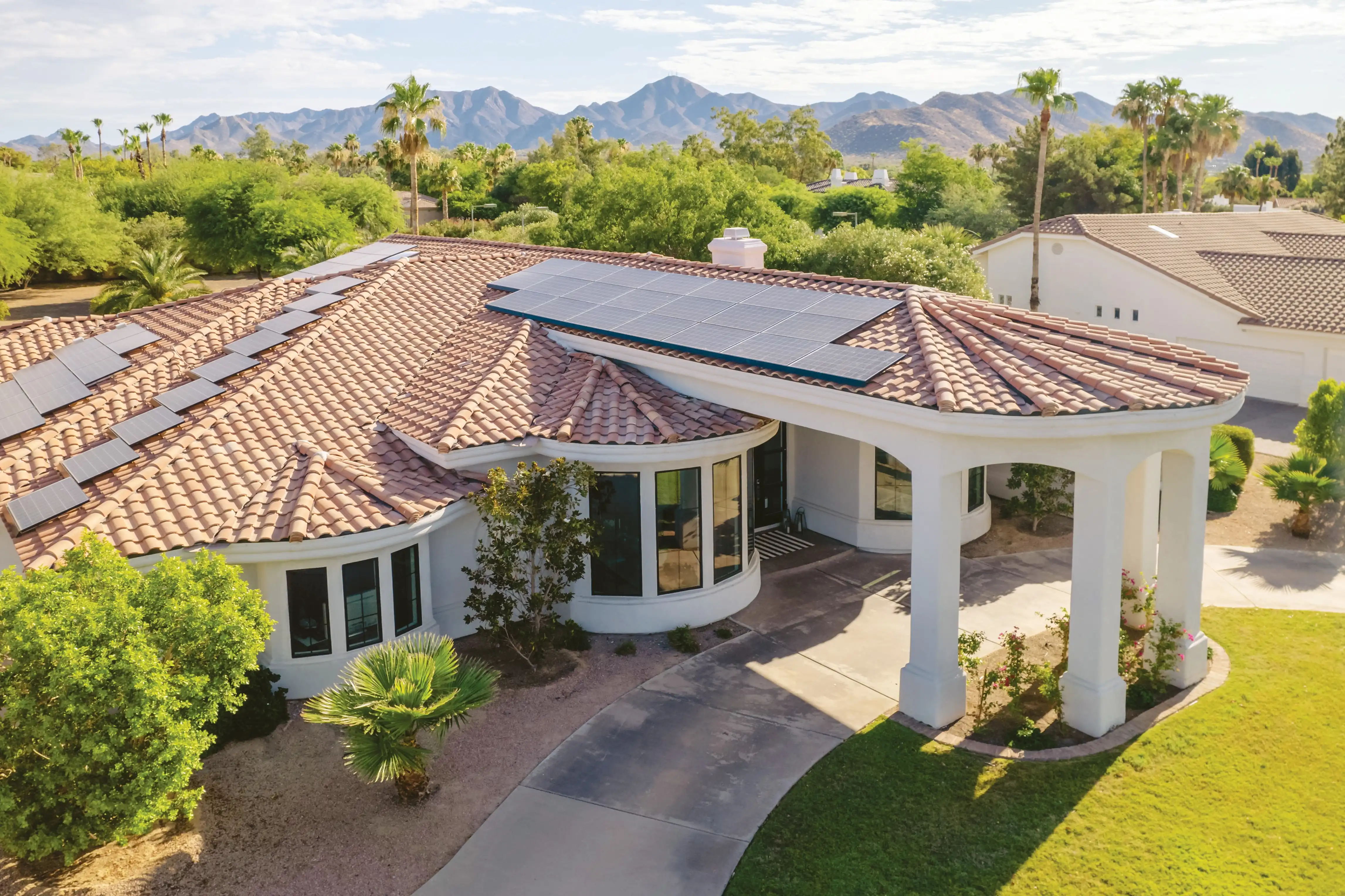 A view of a Spanish style home from a drone featuring lots of windows.