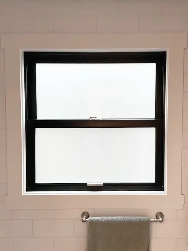 Interior view of a single hung window in a bathroom with privacy glass.