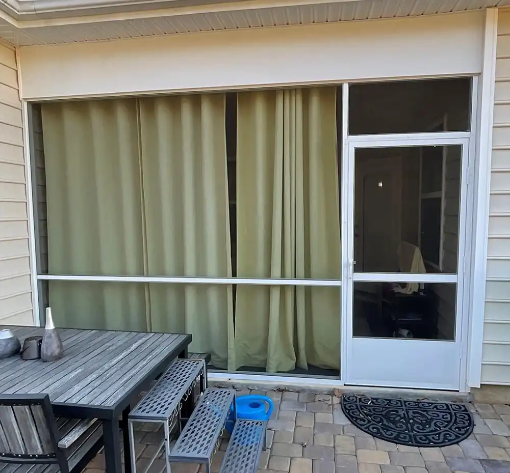 Exterior view of a patio with a storm door and screened three-season porch.