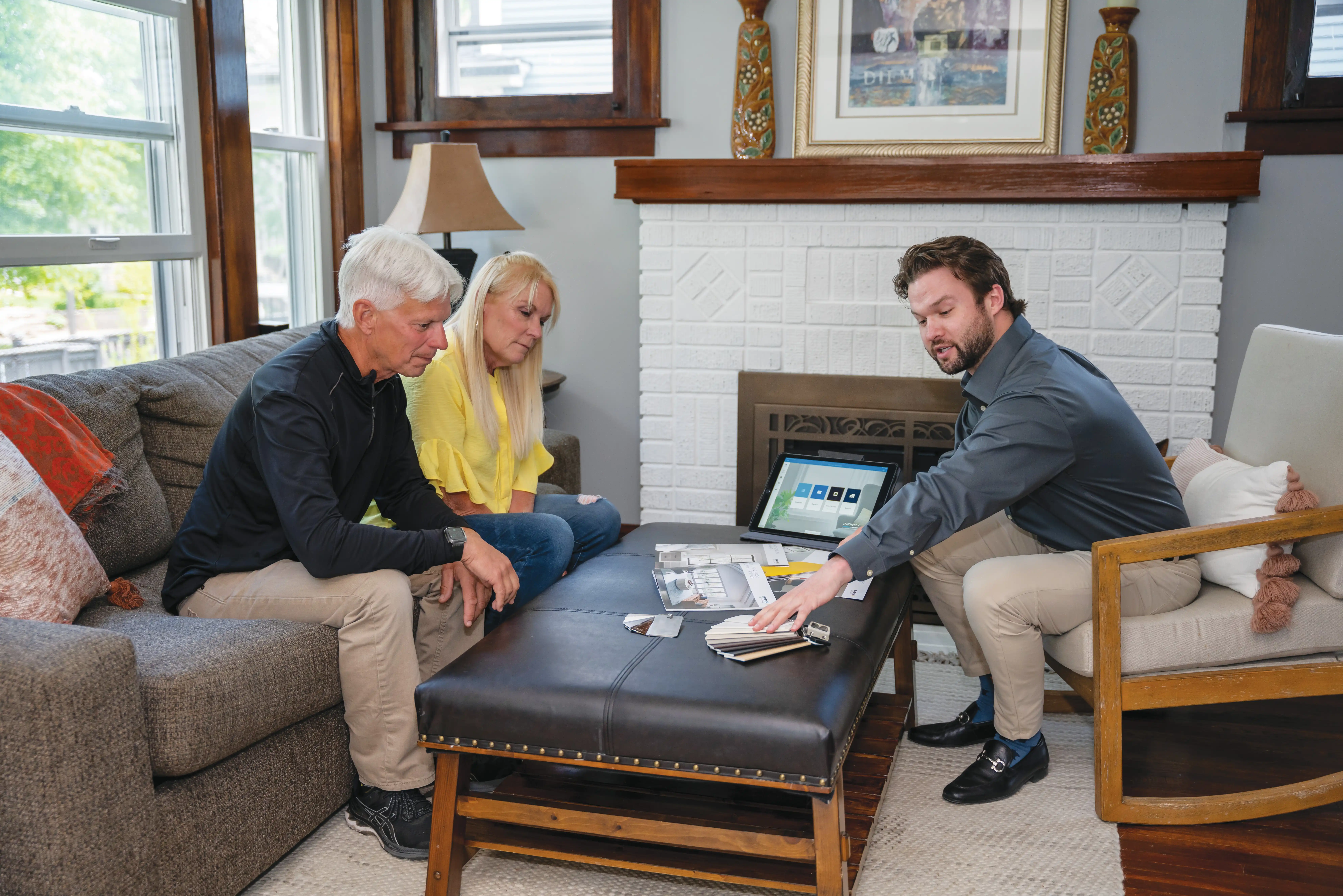 A Marvin Replacement design consultant talks with a middle aged couple about window and patio door design options in a living room.